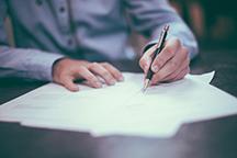 Person signing forms at a table